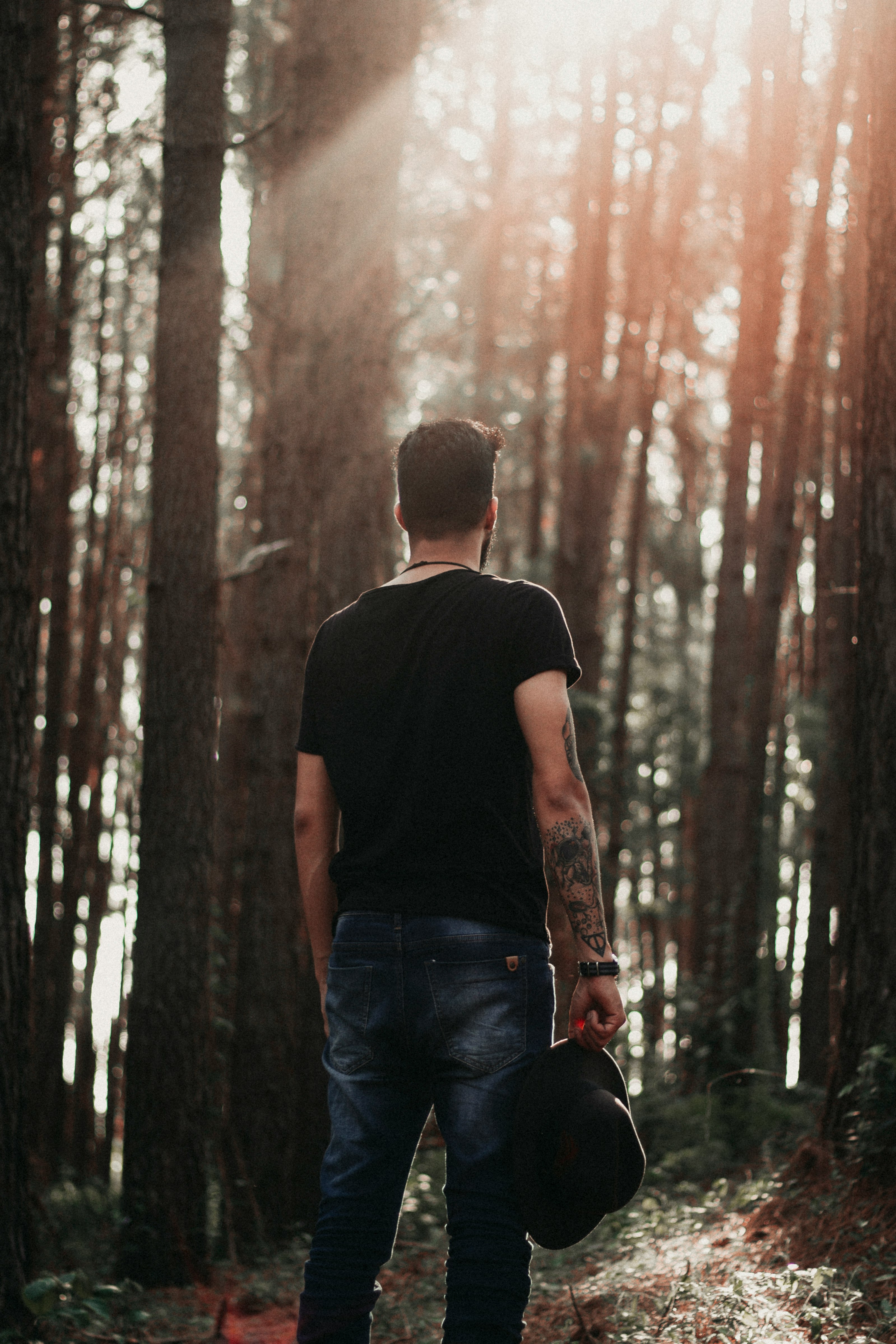 man holding cap standing in forest